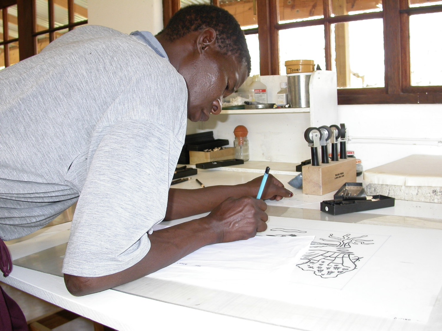 Artist Ditiro Makwena drawing on grained film for a lithograph of his at The Artists' Press.