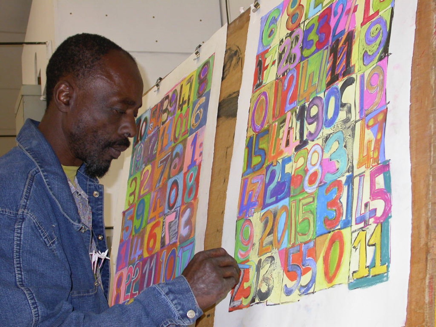 Dumisani Mabaso drawing onto two of his brightly coloured lithographs at The Artists' Press