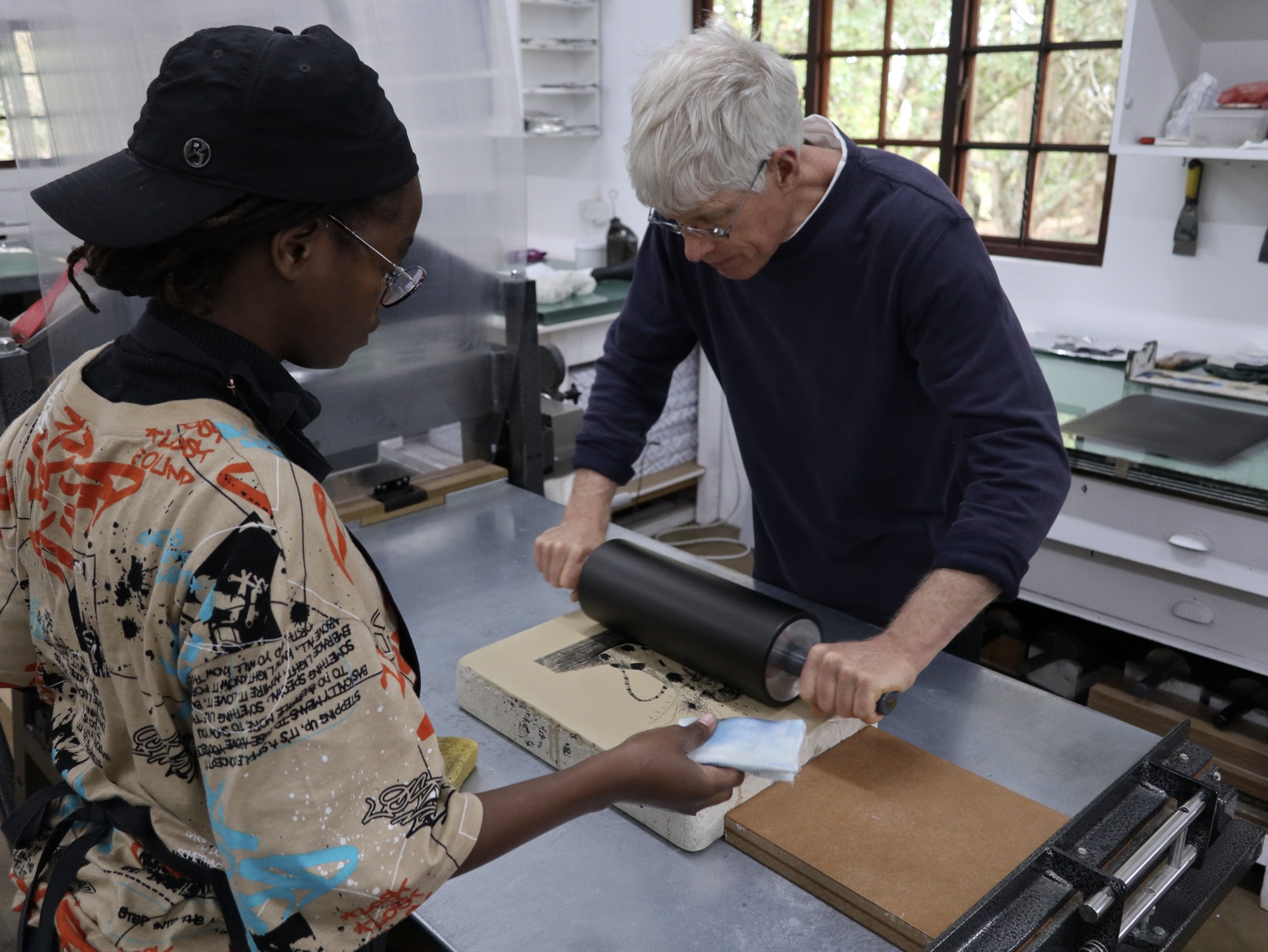 two people printing a lithograph from stone on lithography press