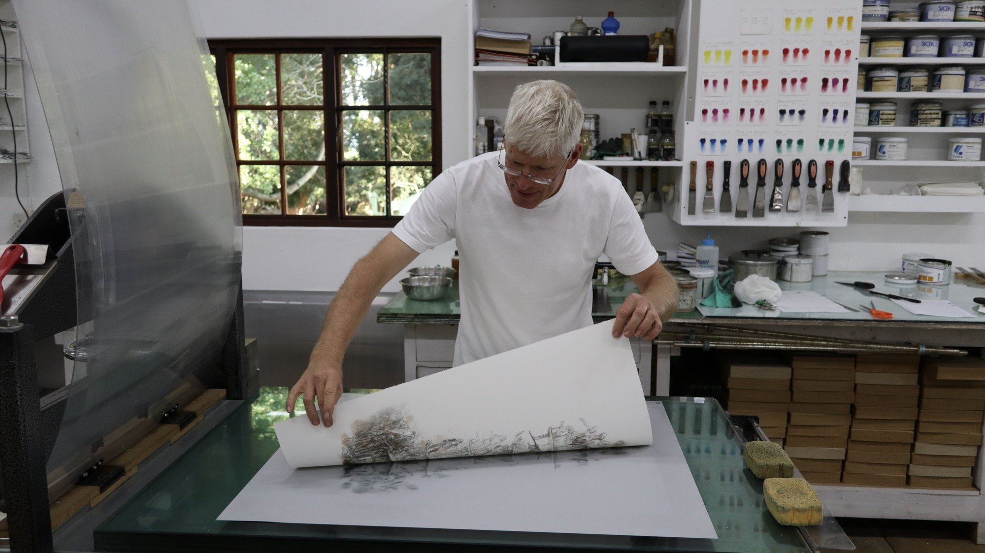 man pulling a print off a hand operated lithography press